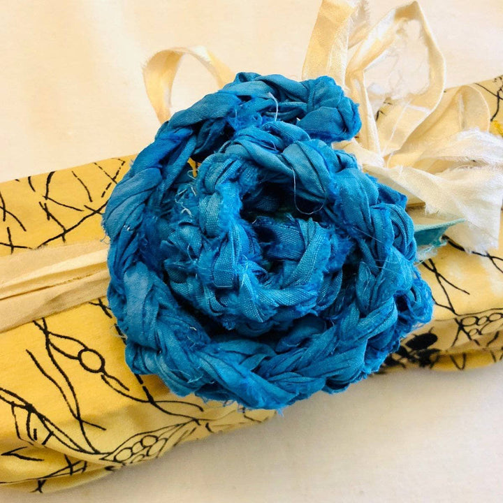 Teal Recycled Sari Silk Gift Bow  over a yellow gift wrapper