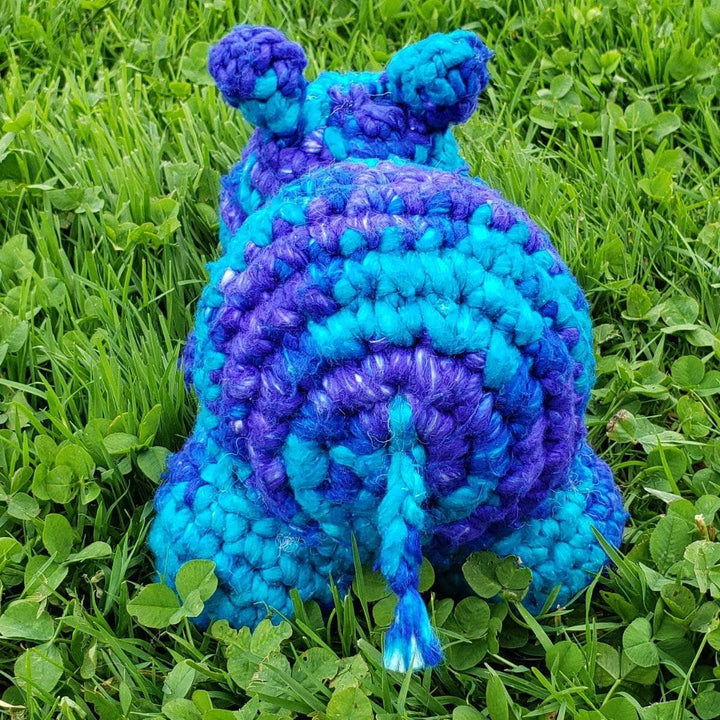 small crochet hippo sitting over the grass