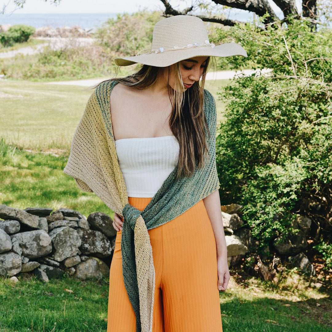 Model wearing herbal dyed recycled silk knit shawl with greenery in the background.
