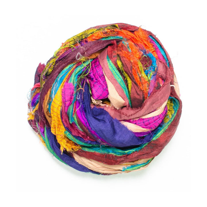 yarn made from reclaimed sari material ribbon in front of a white background.