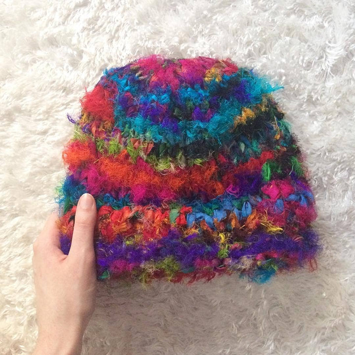 hand holding a colorful beanie