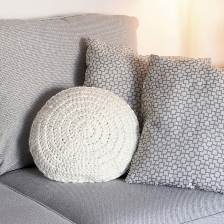 a white pillow on a grey couch