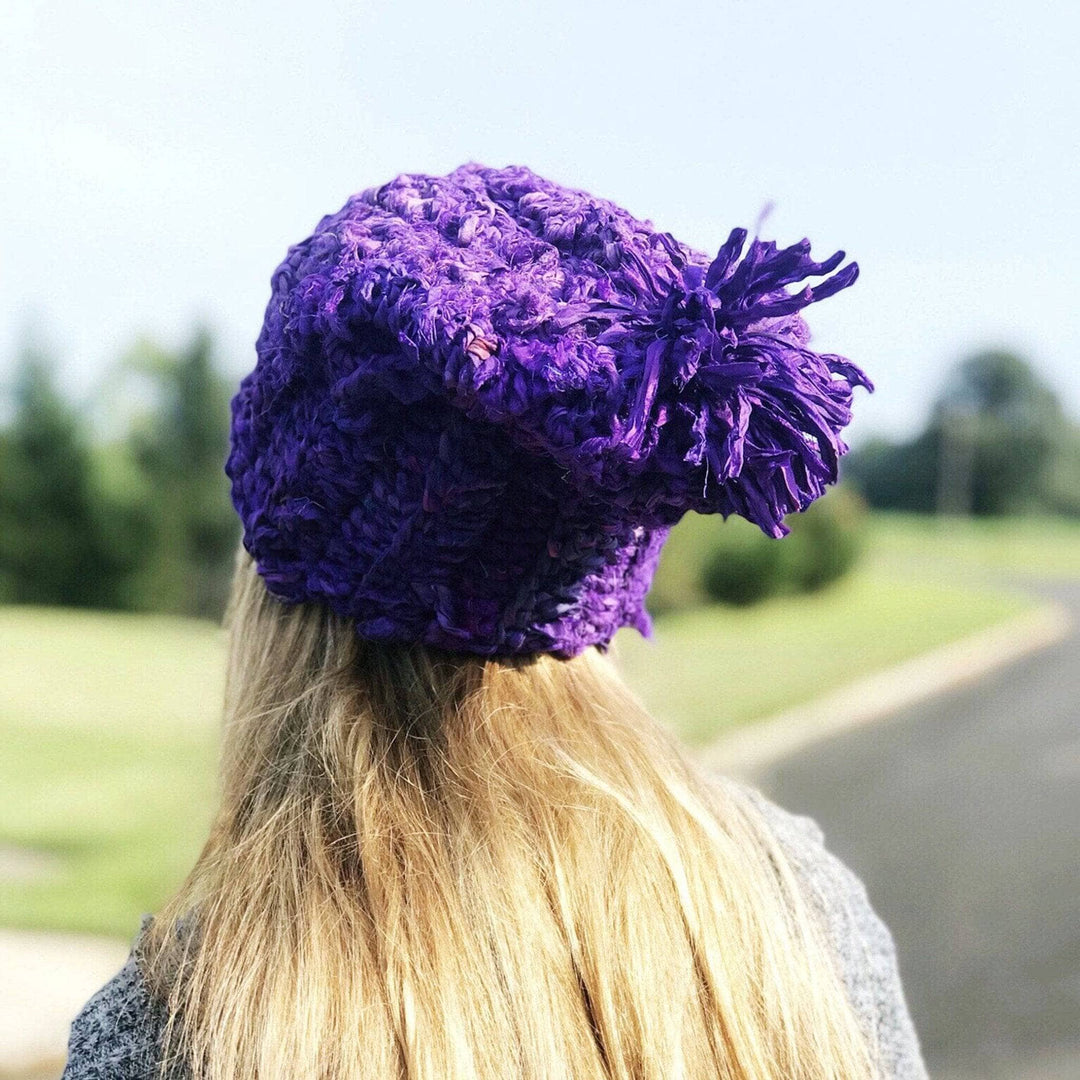 A back view of a girl wearing a purple sari ribbon hat outside