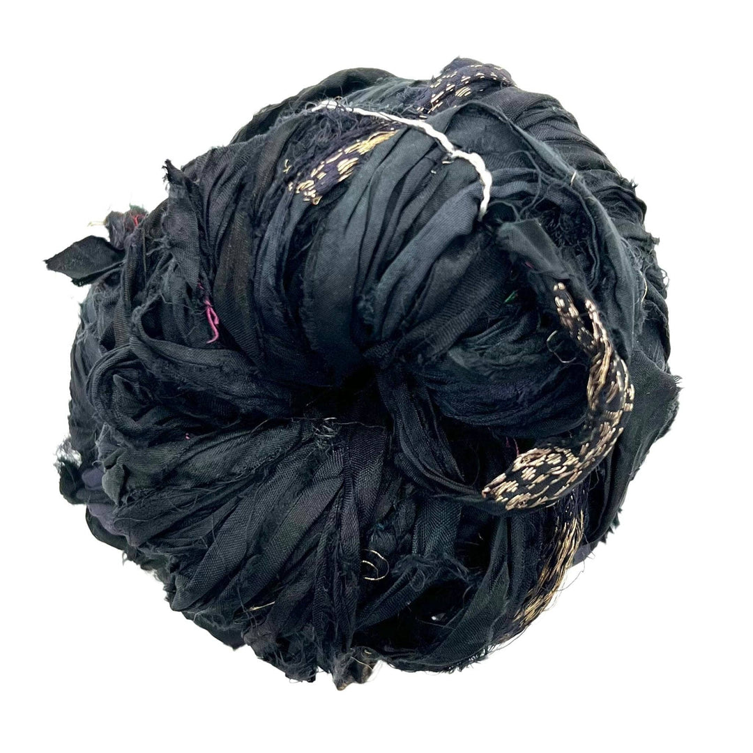 A skein of reclaimed sari silk ribbon in the colorway 'black' sitting on a white background.