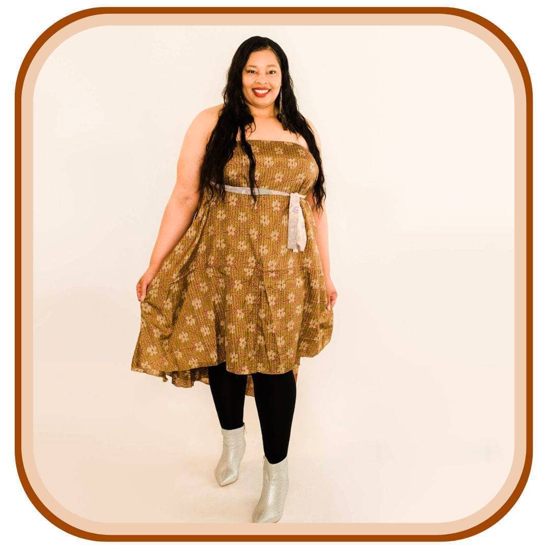 Model Stands against a white background. She wears a light brown dress with a tan floral pattern. She also wears black leggings and silver shoes. 