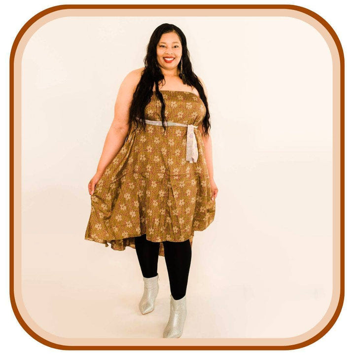 Model Stands against a white background. She wears a light brown dress with a tan floral pattern. She also wears black leggings and silver shoes. 
