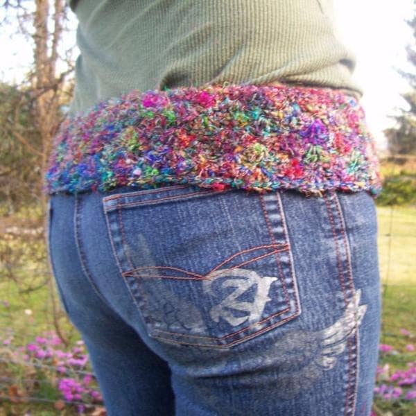 Side view of a woman wearing a thick belt made of multicolored yarn outside
