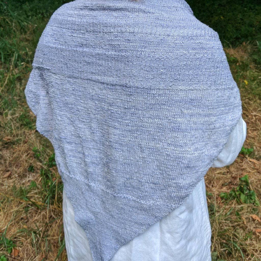 A back view of a women wearing a gray shawl outside 