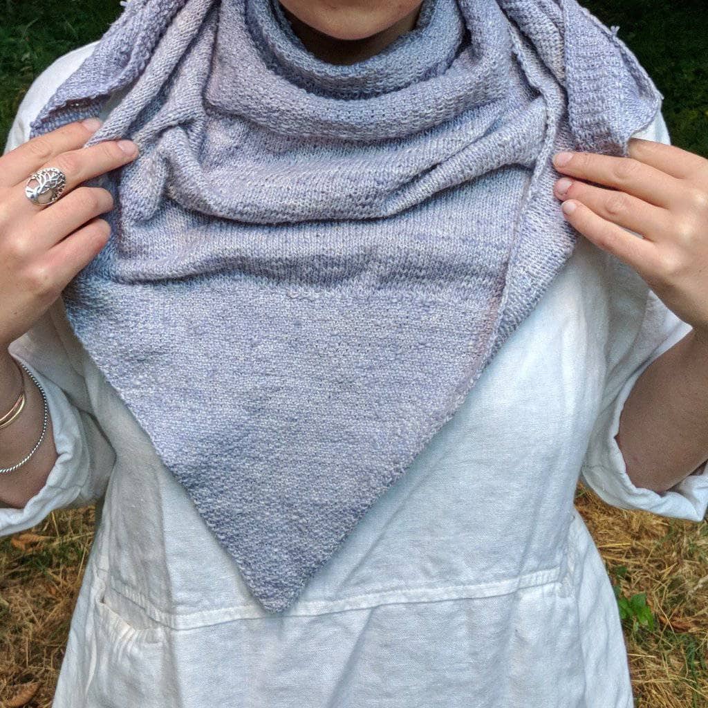 A front view of a women wearing a gray shawl outside 