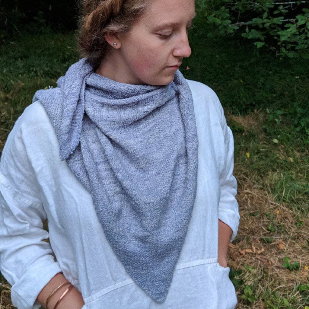 A front view of a women wearing a gray shawl outside 