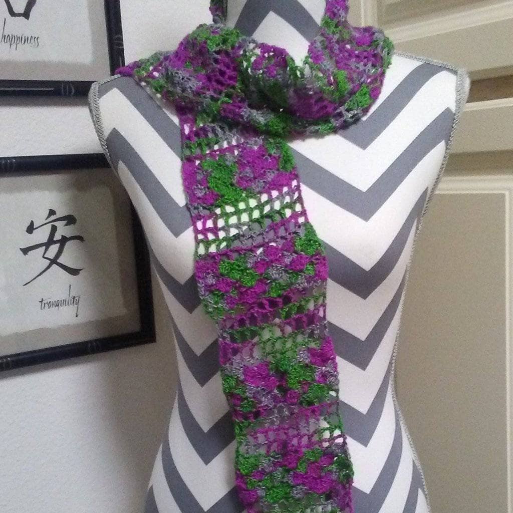 A purple and green scarf on a white and gray mannequin with a white door in the background