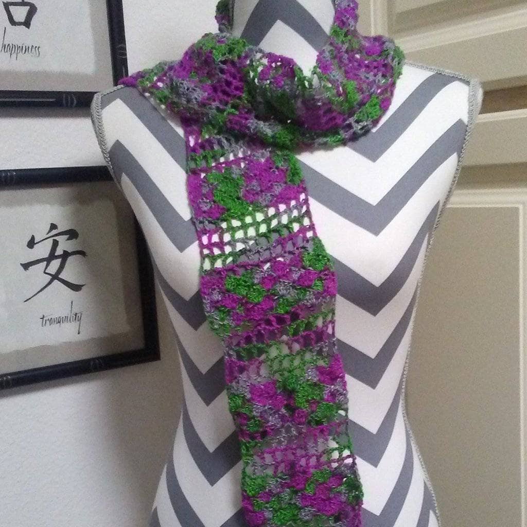 A purple and green scarf on a white and gray mannequin with a white door in the background