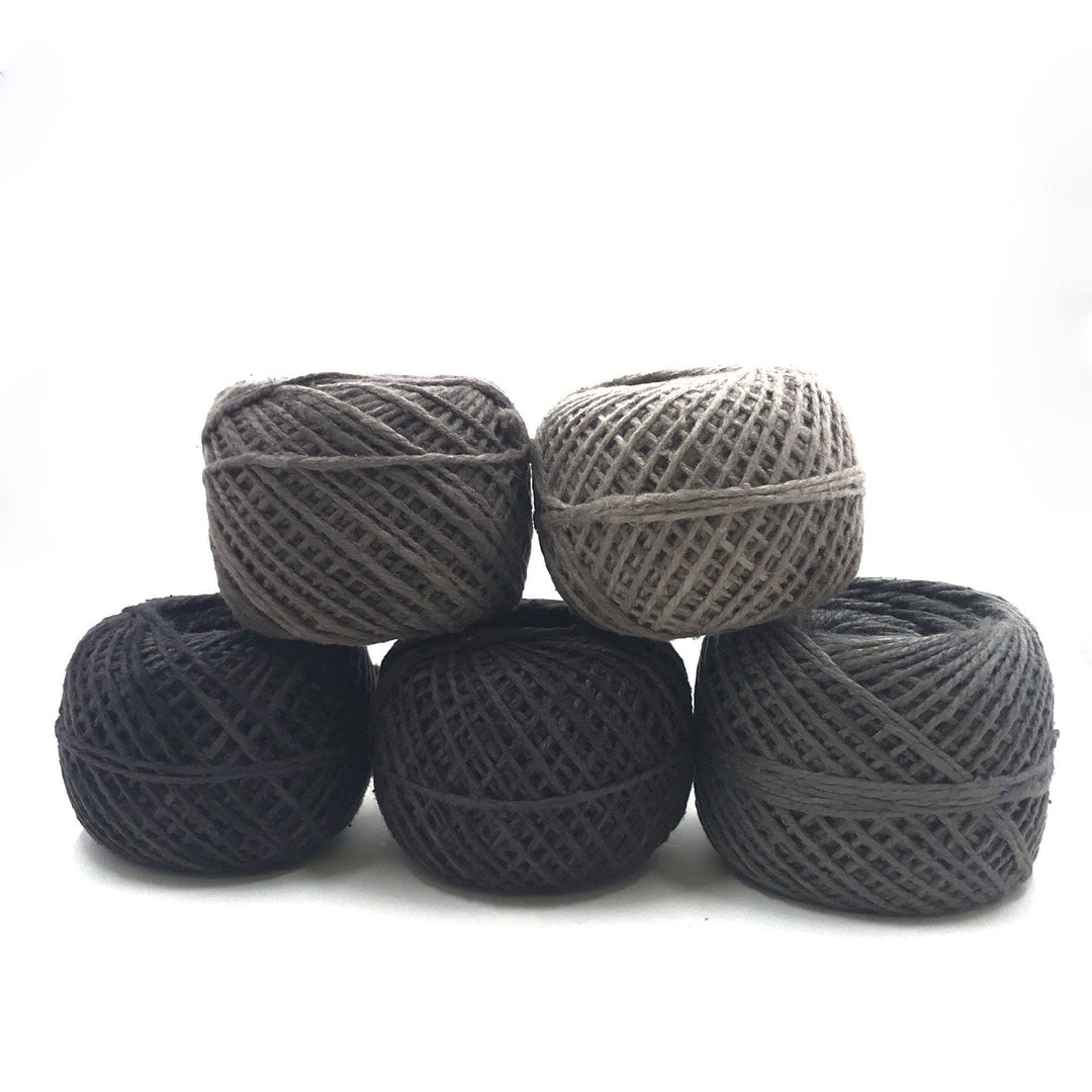 A gray ombre of five cakes of yarn on a white background