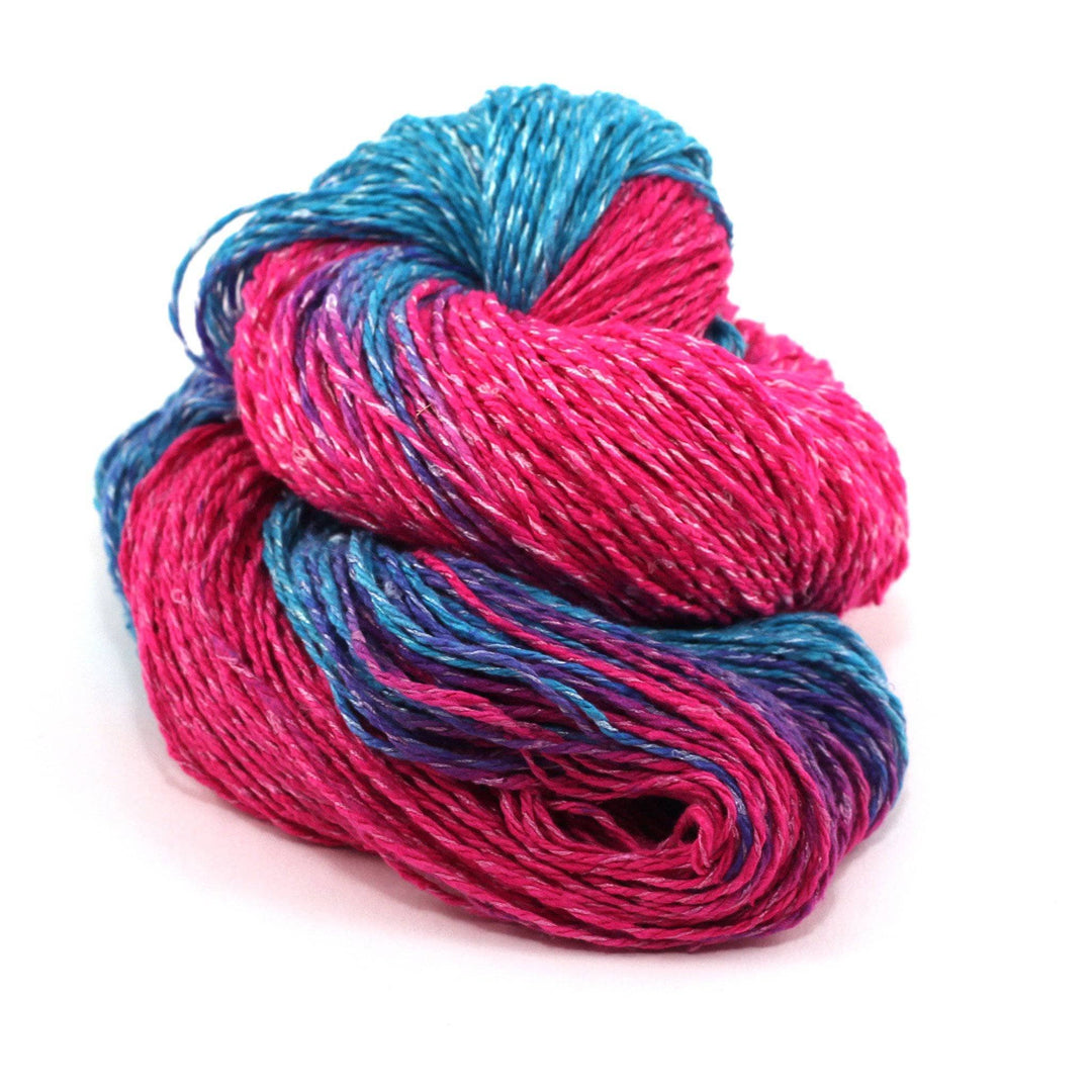 Variegated pink and blue skein of silk blend sport weight eighty-twenty rule yarn on a white background