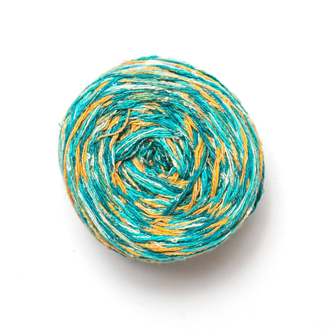 top view of silk blend sport weight yarn in colorway island glow (turquoise and golden yellow variegated).