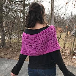A back view of a woman wearing purple pink shawl wrap with trees in the background 