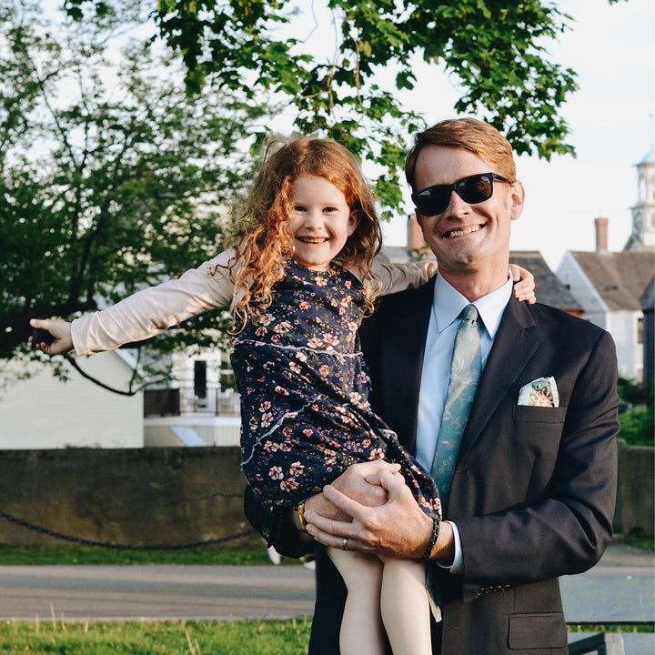 Father and daughter in a park. Father is wearing the silk neck tie and pocket square. 