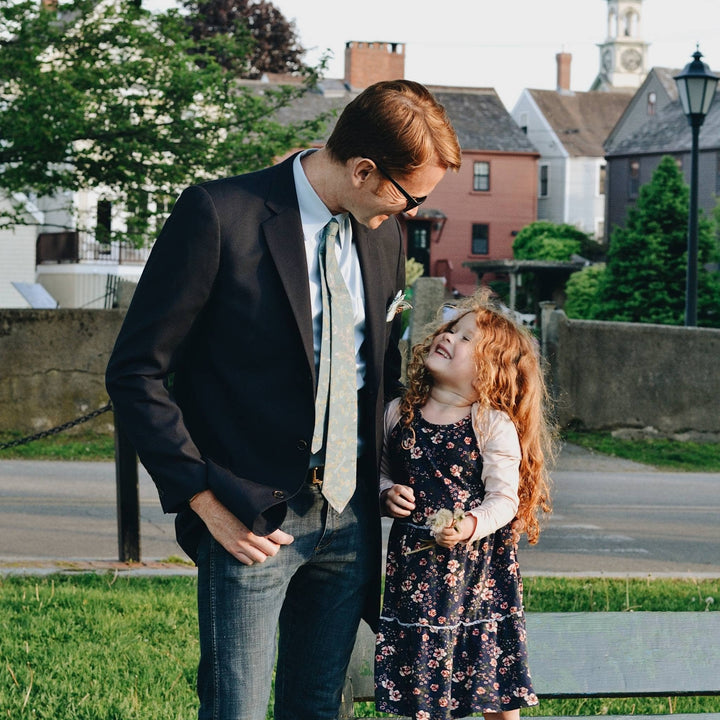 Father and daughter standing in a pack. Father is wearing the silk neck tie in green. 
