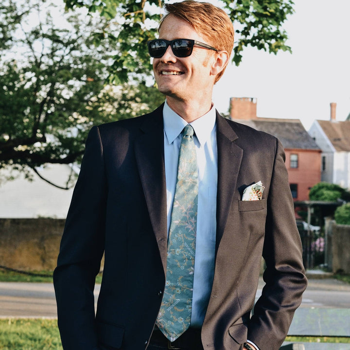 Model is wearing a green silk neck tie and pocket square. 