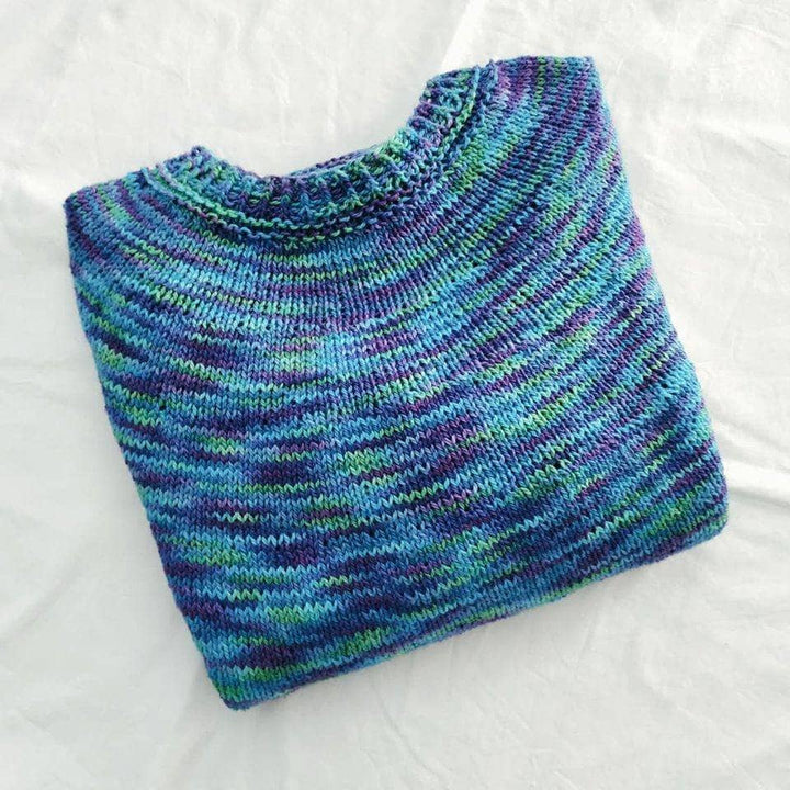 Image of simple seamless sweater in colorway peacock folded and sitting in front of a white background.