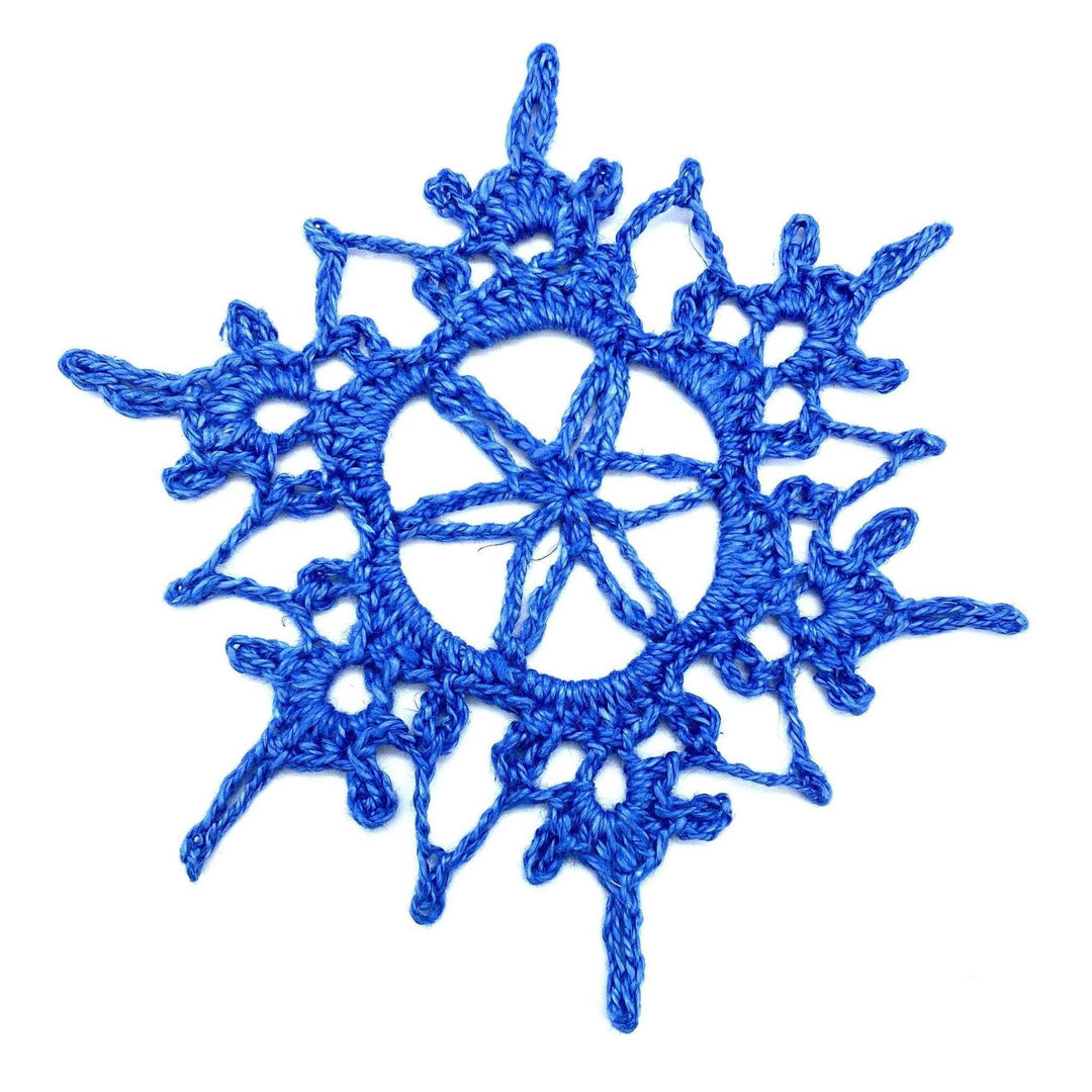 crochet blue linen yarn snowflake in front of a white background.