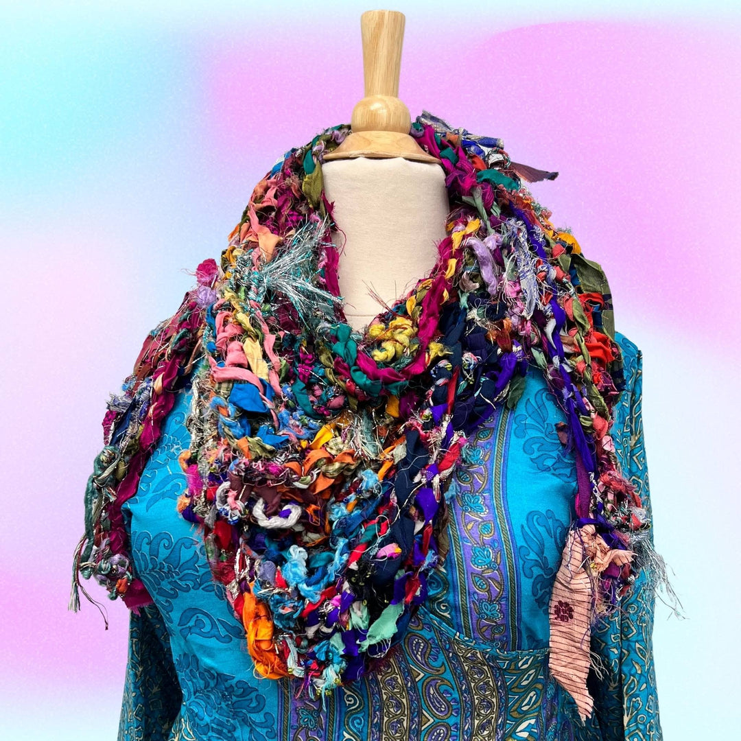 Mannequin wearing sparkle me shawl and zaria wrap dress in front of a pastel purple and blue background. 