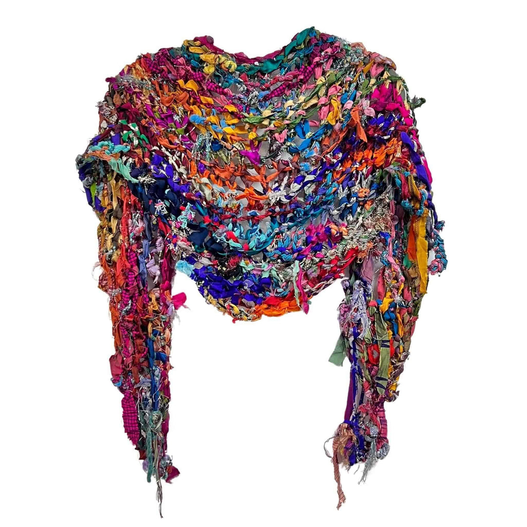 Sparkle me shawl hanging on a hanger in front of a white background.
