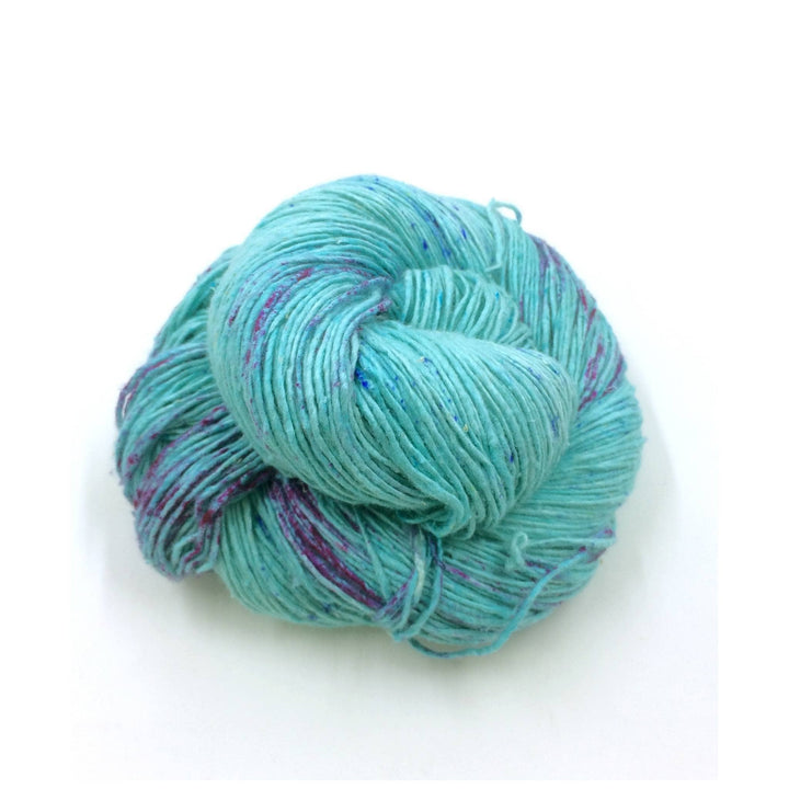 Sport weight silk yarn in Caribbean Current (turquoise and purple) in front of white background.