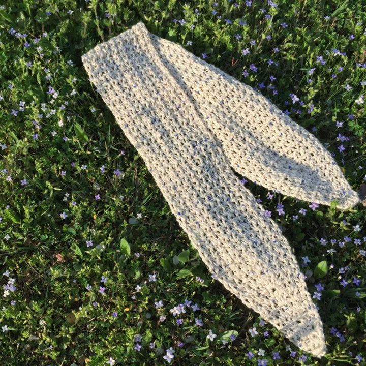 White crochet scarf with blue beads on a bed of forget me not flowers during golden hour.