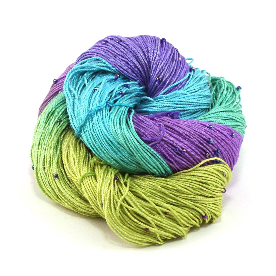 Hand beaded lace weight yarn ball in Moody Blues (blue, purple, green) on a white background