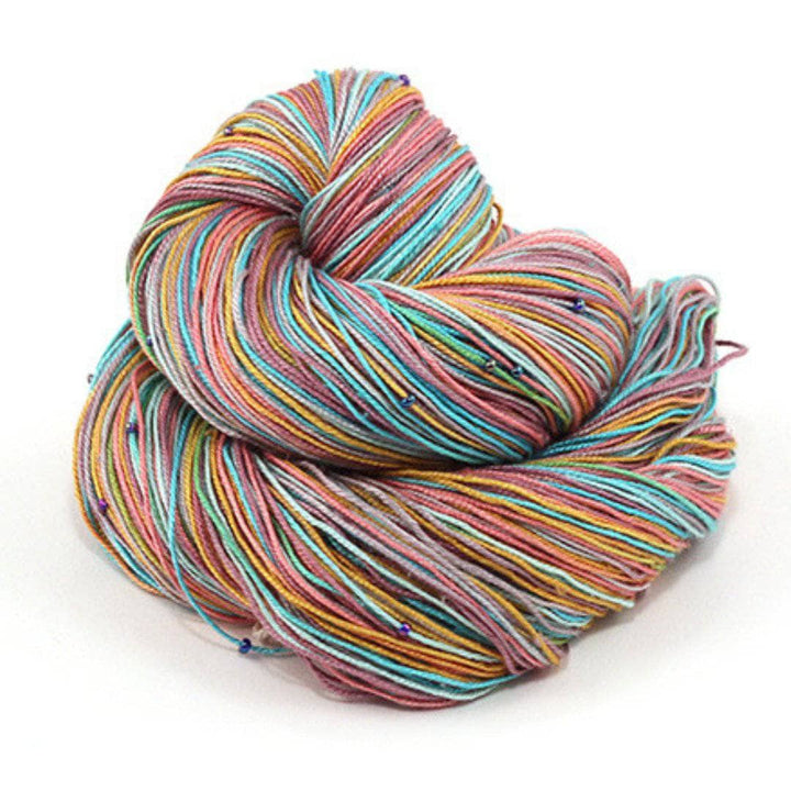 Hand beaded lace weight yarn ball in Rainbow Row (multicolored) on a white background