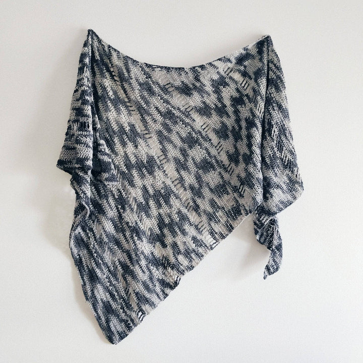 A monochromatic Shawl hanging on a a white wall