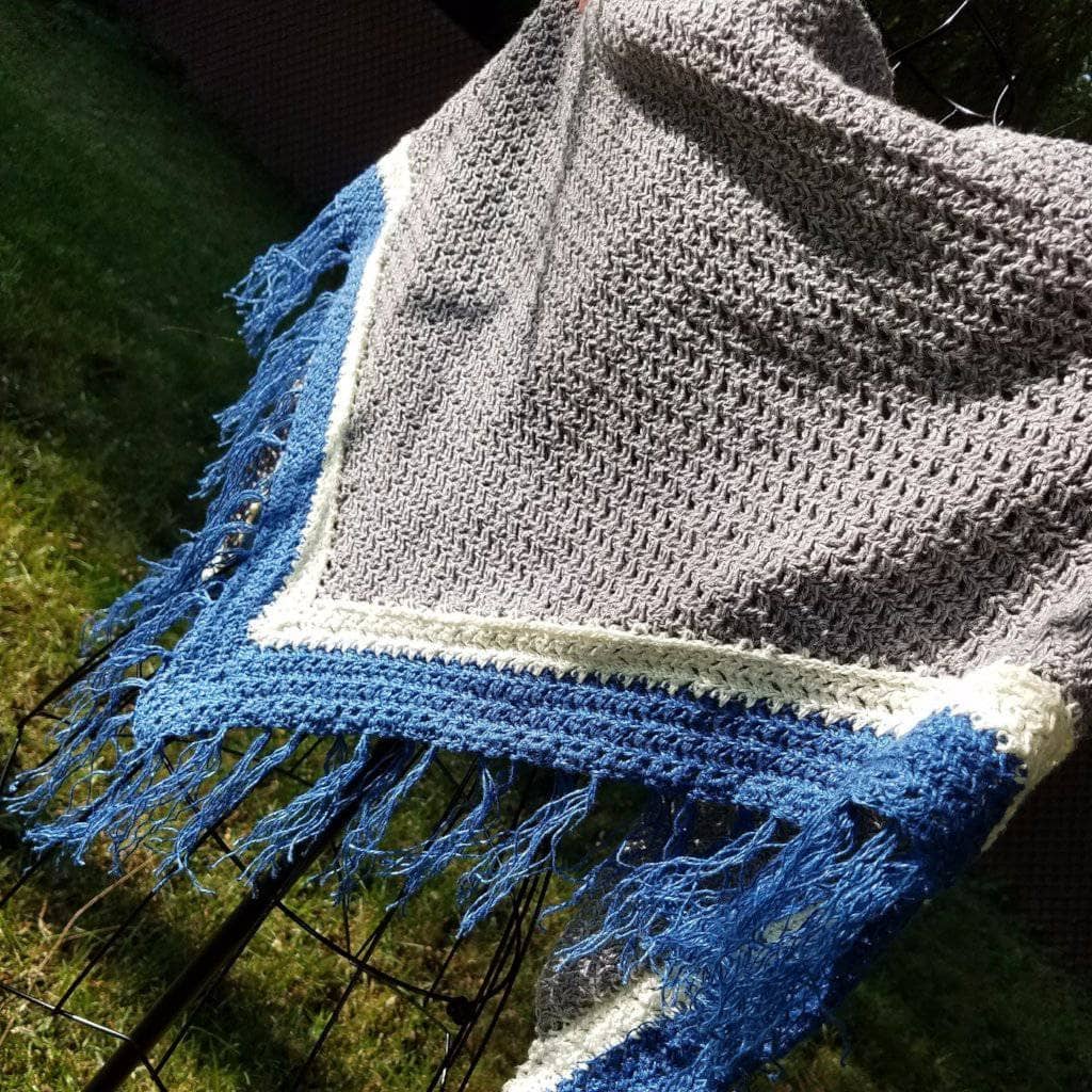 shawl spread out on wire mannequin with grass in the background