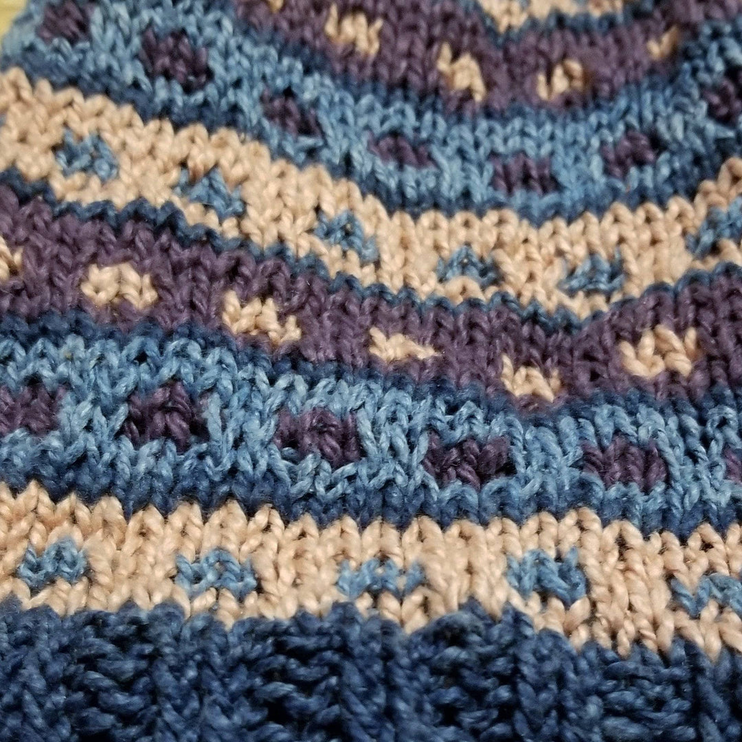 Blue, purple, and pink stripe and dot pattern made out of yarn