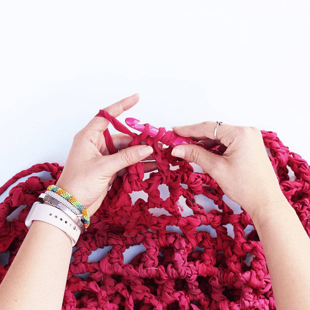 Close up of woman's hands making the summer Nights Chiffon Crochet Shawl on a white background
