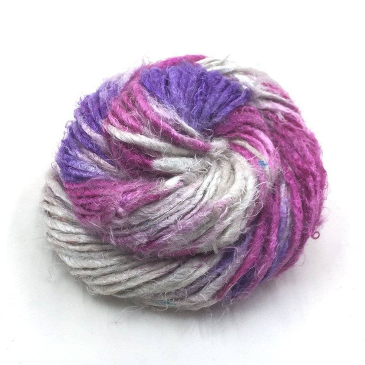 Banana fiber yarn donut ball in Mulberry Swirl (pink, purple, gray) on a white background