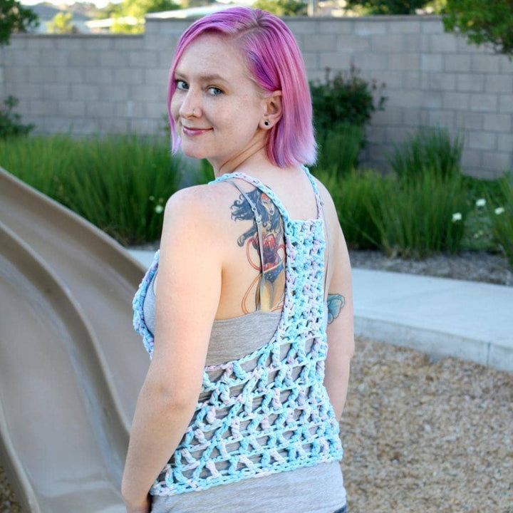 Woman with pink hair wearing The Celia Tank Top in front of a children's playground