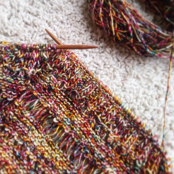 In progress picture of a yellow and red speckled shawl 
