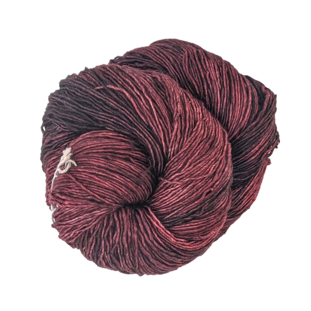 skein of swamp (tonal red) yarn in front of a white background.