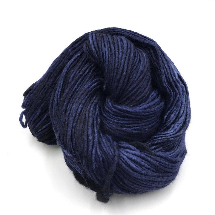 skein of single ply tonal deep blue malabrigo wool yarn in front of a white background.