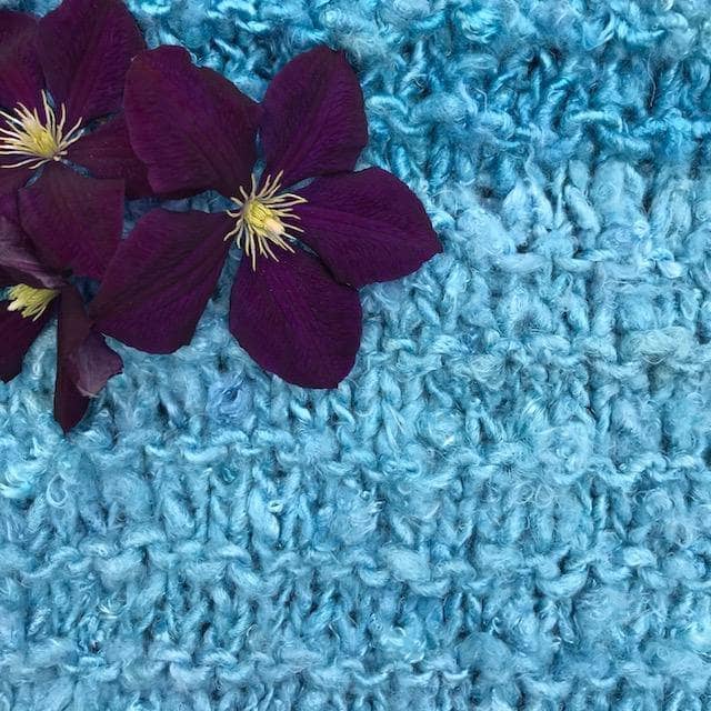 Close up of The Ocean Waves Cowl in Sea Mist (blue) with purple flowers