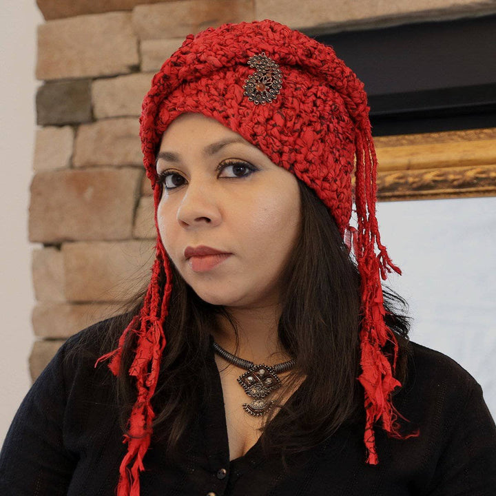 Woman wearing The Red Taj Headscarf in Paisley Red and standing in front of brick 