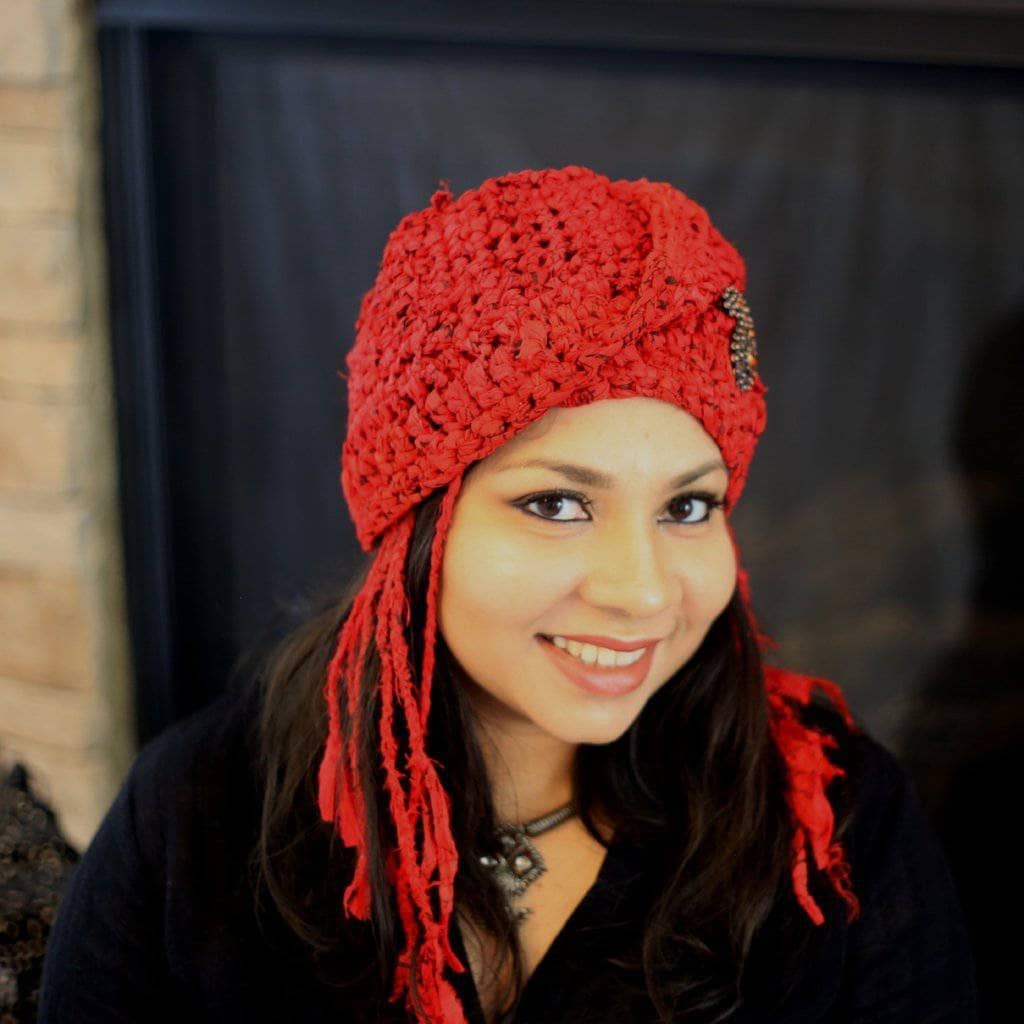 Woman wearing The Red Taj Headscarf in Paisley Red and standing in front of a black wall