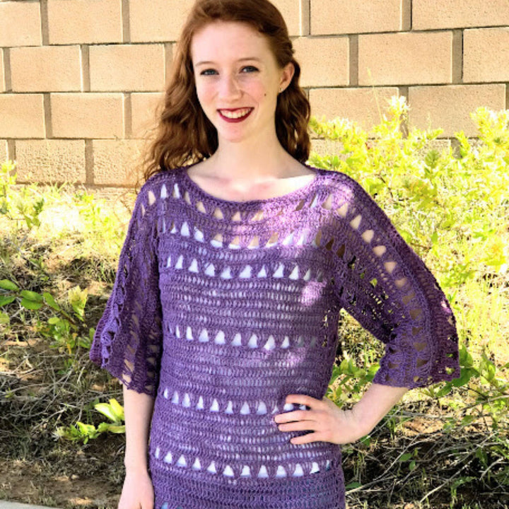 An up close shot of a woman standing outside wearing a Shelby Crochet Crop top made with purple 2-ply linen yarn.