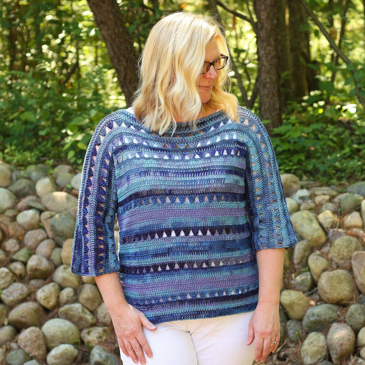An up close shot of a woman standing outside wearing a Shelby Crochet Crop top made with cadet blue 2-ply linen yarn.