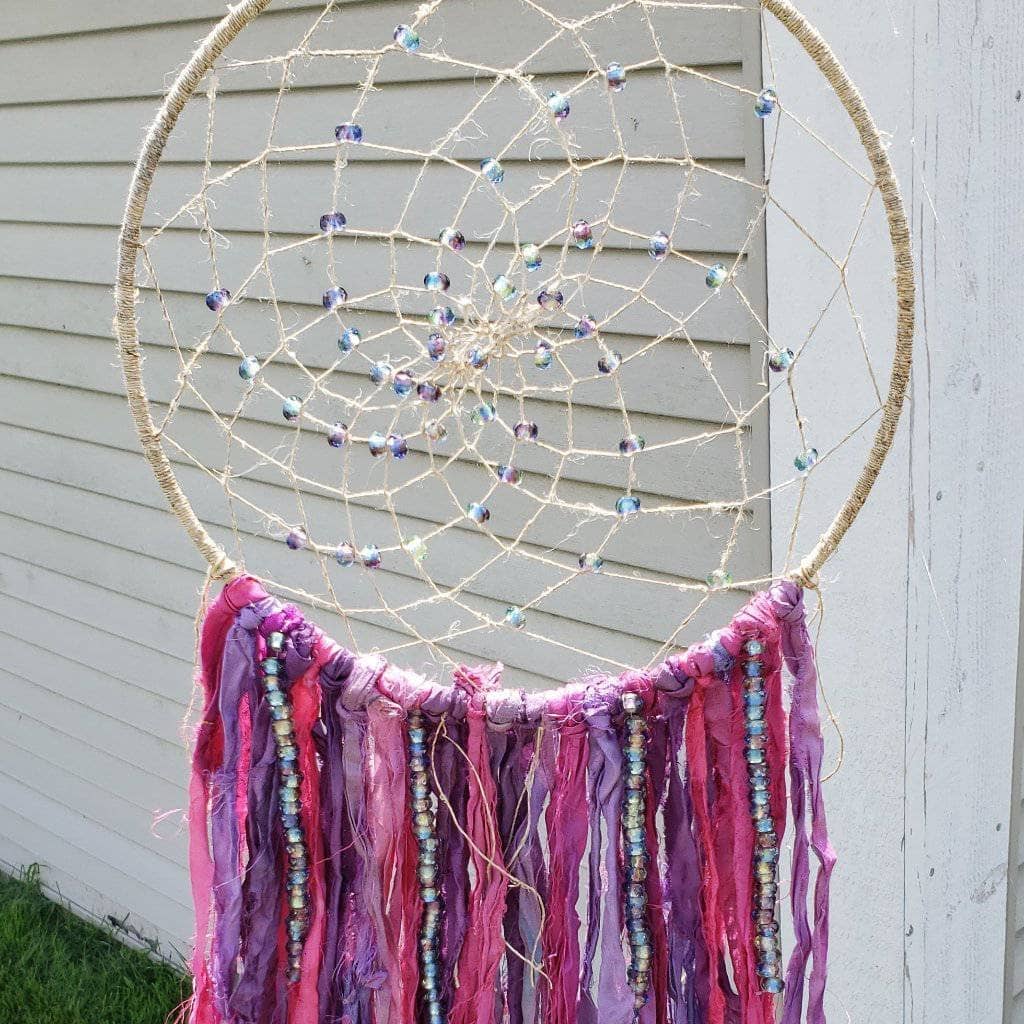 The Simple Dreamcatcher in pinks hung in front of a white wall