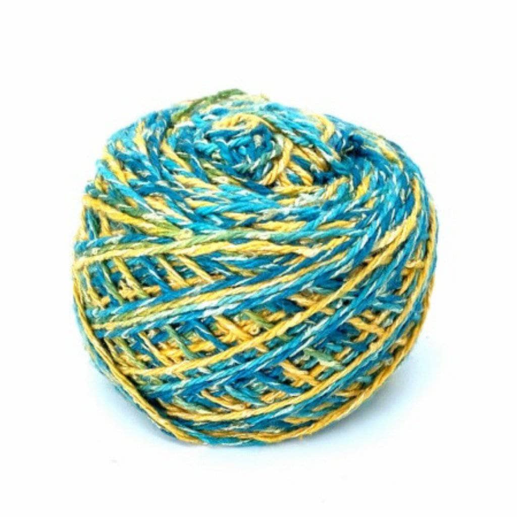 Single cake of sport weight silk blend yarn in the colorwat island glow (blue and yellow variegated) in front of a white background.