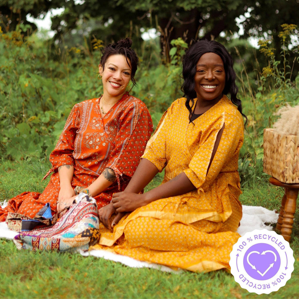 Two girls having a picnic in the park wearing warm tone Zaria Wrap Dresses