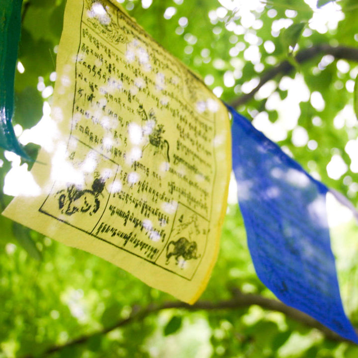 Close-up view of a yellow tibetan prayer flag hanging in a tree