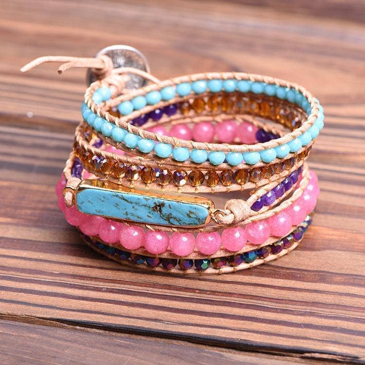 turquoise and pink wrap bracelet coiled up sitting on a wooden background.